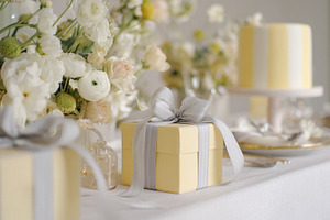 Yellow gift box with silver ribbon on an elegant party table cel, a Photo by Studio ANNA