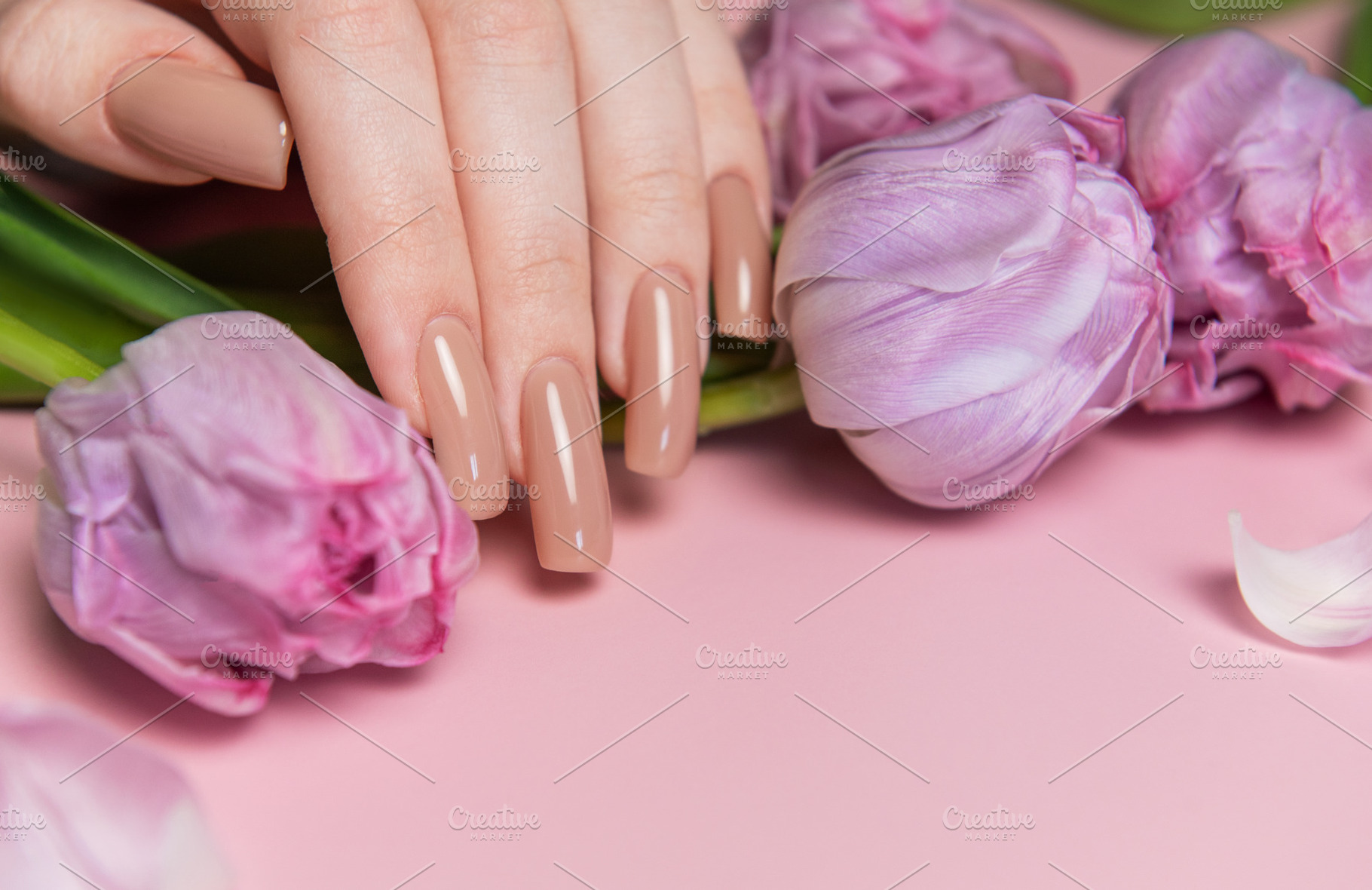 Woman showing nude manicure and pink tulips on pink background, a Beauty & Fashion Photo by Olena Rudo