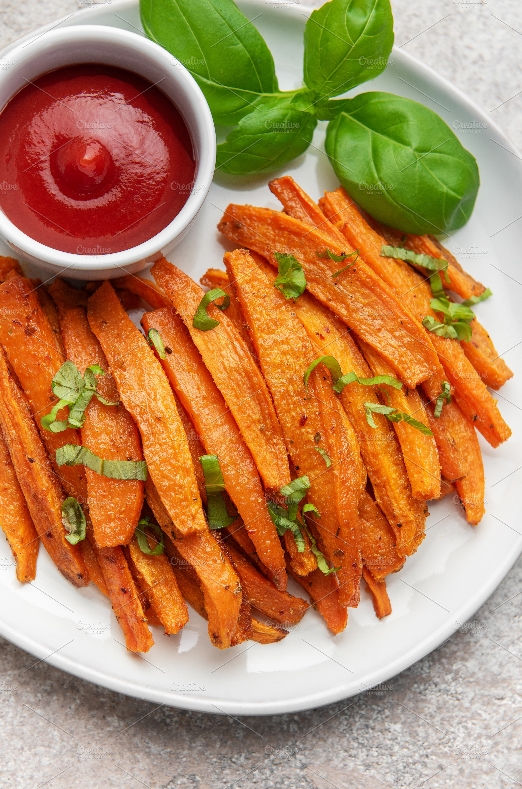 Sweet potato fries with ketchup and basil serving on plate, a Food & Drink Photo by Olena Rudo