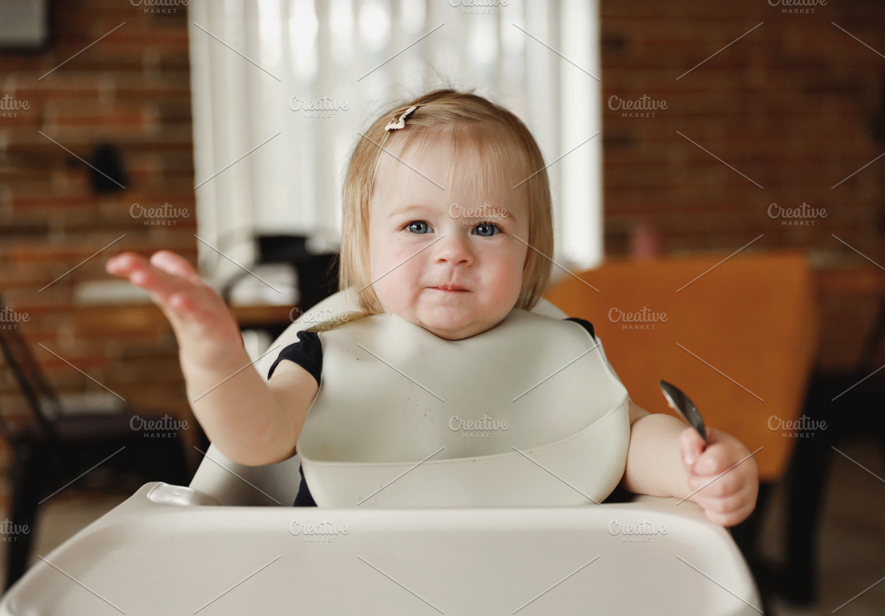 Infant girl or toddler sitting on high chair. Eating food by herself using spoo, a Person Photo by Lenor4ik
