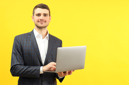 Businessman with laptop on yellow background, space for text, a Person Photo by AtlasStudio PRO
