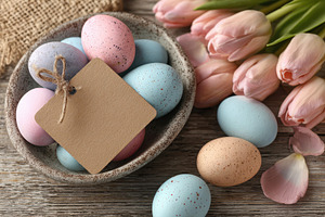 Pastel easter eggs in a bowl with tulips, a Holiday Photo by AlyaAnd
