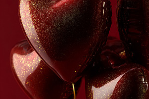 Red heart balloons with golden glitter on a deep red background, a Photo by Studio ANNA