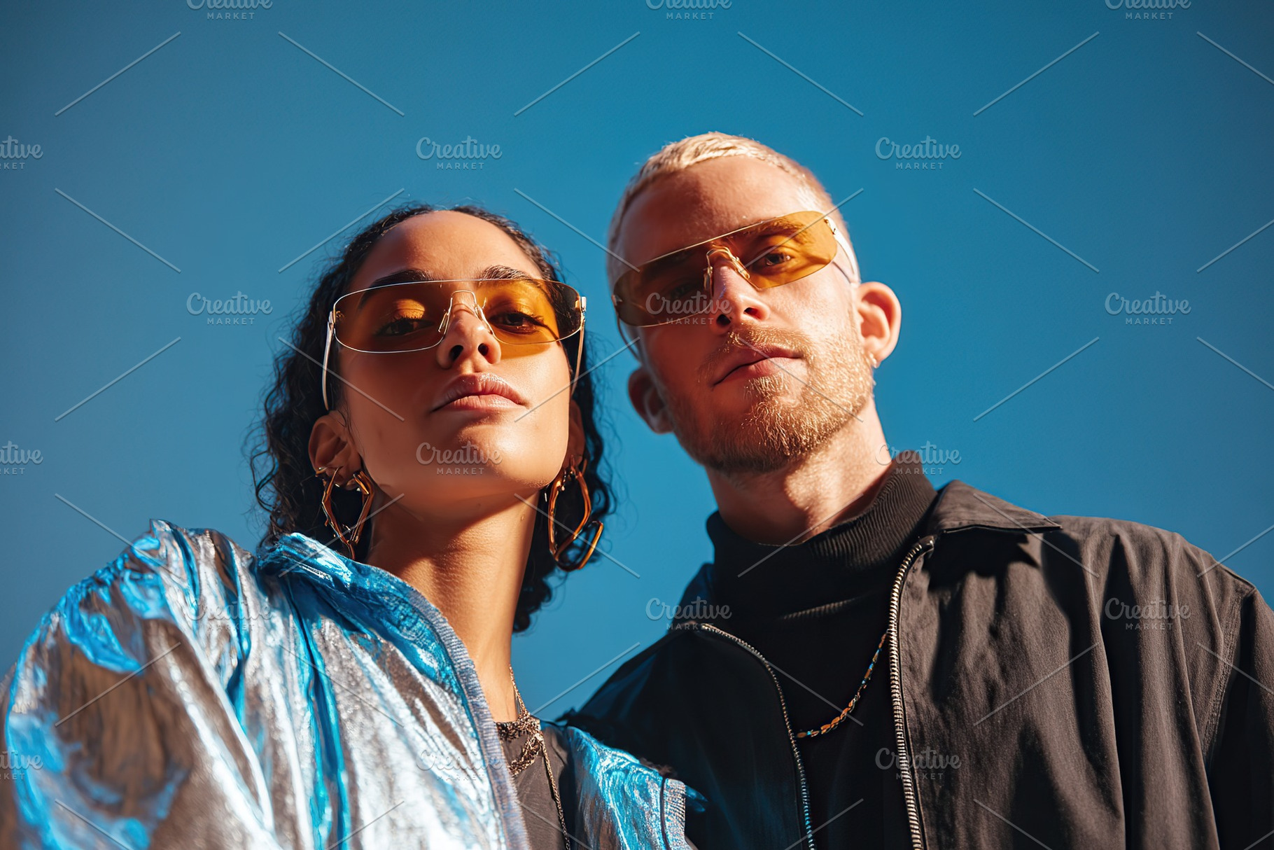 Couple posing in stylish sunglasses against a clear blue sky on a sunny day, a Photo by AlyaAnd