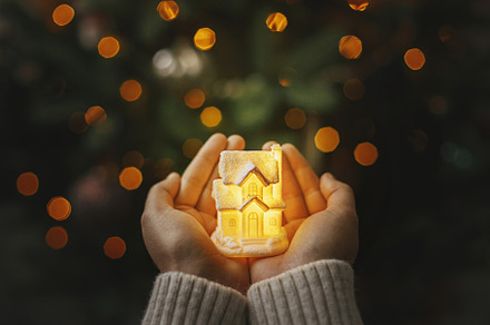 Merry Christmas! Little glowing house in hands at christmas tree, a Holiday Photo by Sonjachni