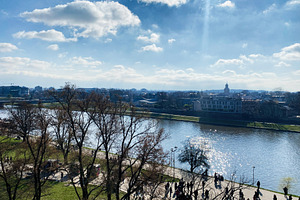 Sunny riverside with trees and people in Krakow, Poland under blue sky, a Photo by AS photostudio