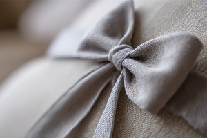 Gray linen bow detail on a pillow, showcasing soft fabric and te, a Photo by Studio ANNA