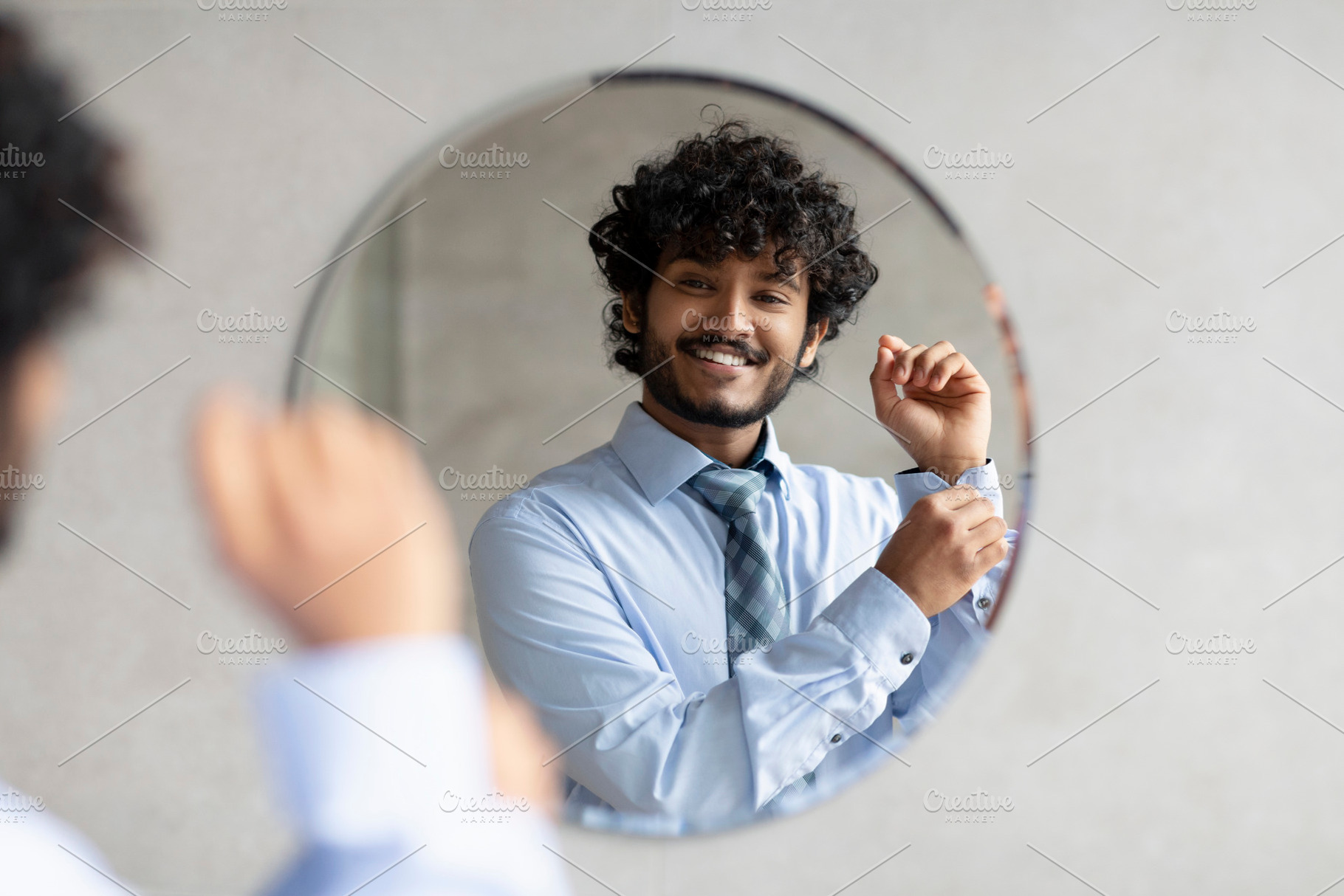 Happy bearded indian businessman standing in bathroom in front of mirror and bu, a Person Photo by Prostock-Studio