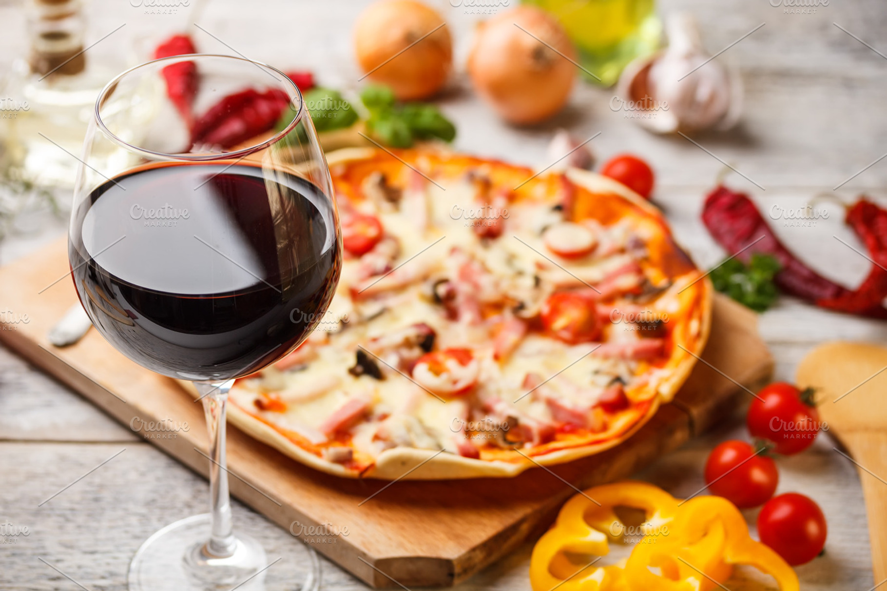 Glass of red wine featuring wine, pizza, and cutting board
