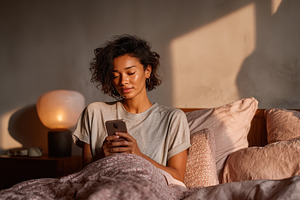 Woman using smartphone in bed mornin, a Photo by Pixeness Studio
