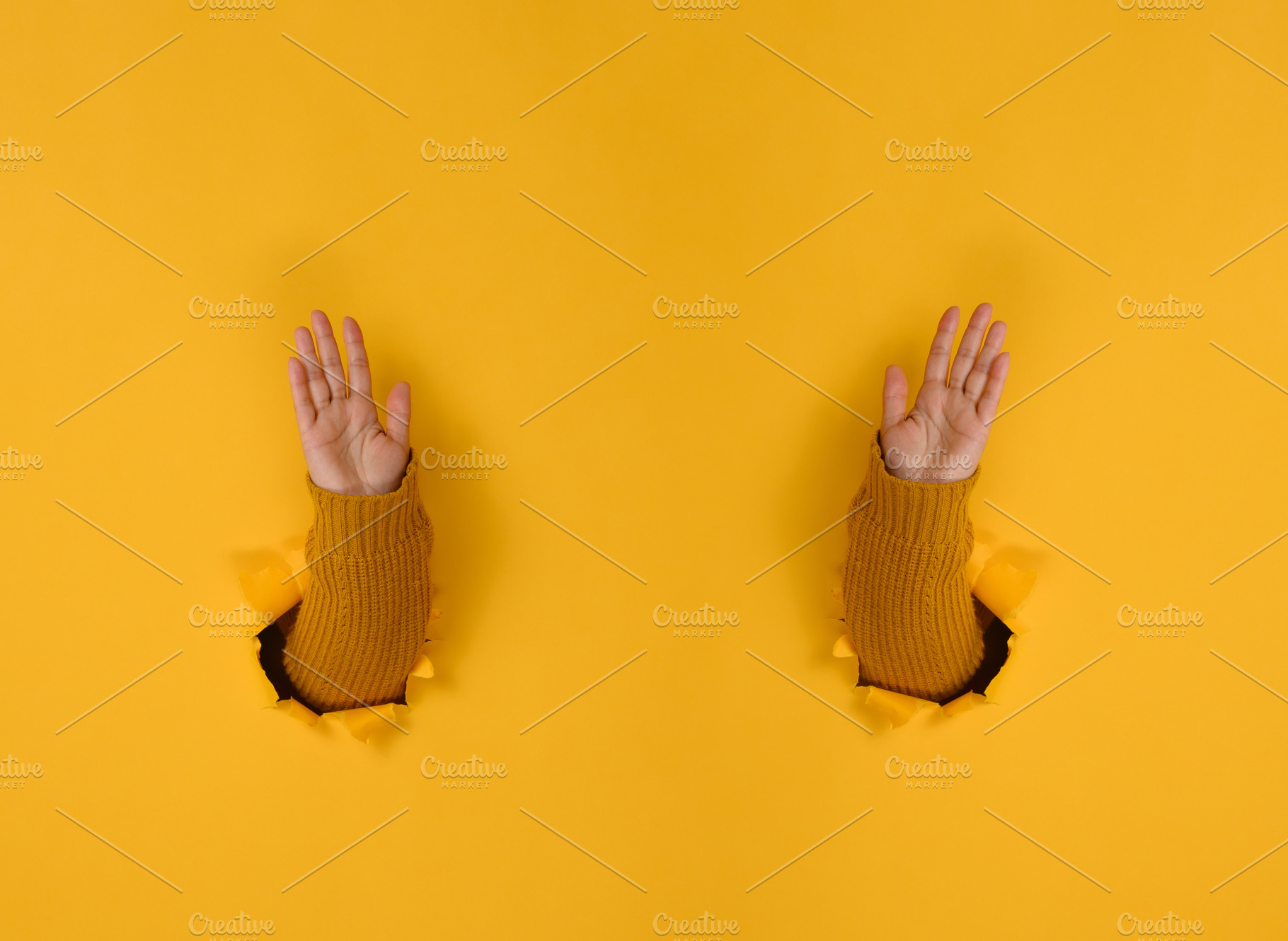 Hands in a yellow sweater pass through holes in yellow paper wit, a Person Photo by ndanko