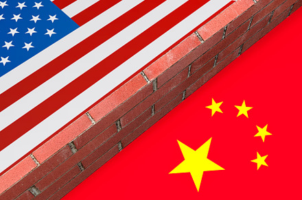 Brick wall dividing United States and China flags