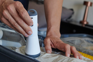 man using a vacuum pump to store clothes in a bag, a Photo by Nito