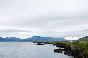 A serene coastline view with rugged cliffs and mountains in Iceland, a Nature Photo by AS photostudio