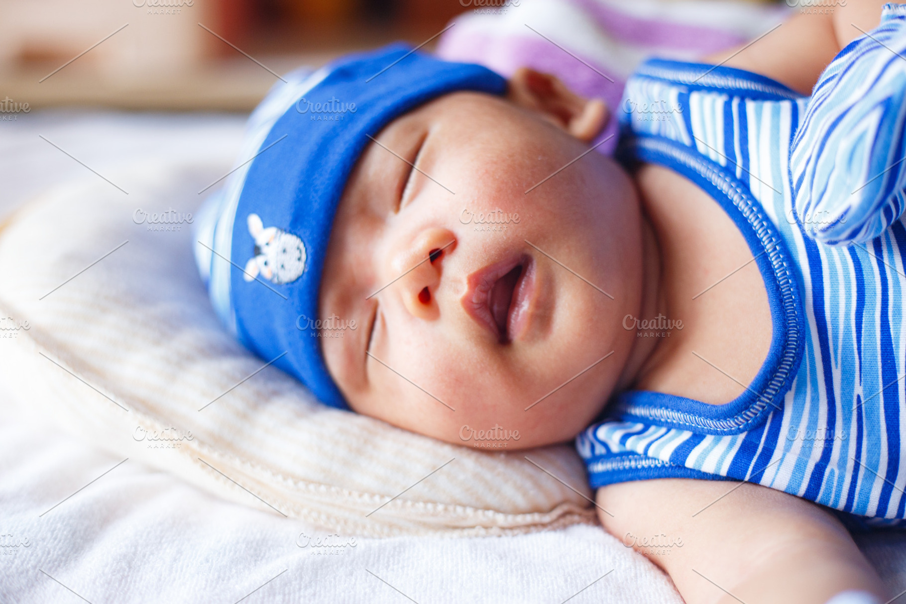 Sleeping baby in blue striped outfit and hat, peaceful expression, a Person Photo by a454