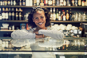 Friendly young African cafe owner leaning on a counter
