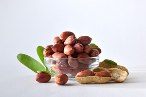 Peeled peanuts in glass bowl isolated on a white table, a Food & Drink Photo by Davizro's Market