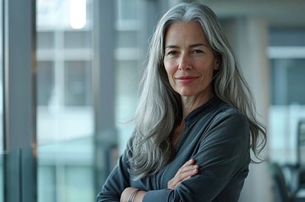 Portrait of attractive mature woman with long gray hair in business office, a Person Photo by AlyaAnd