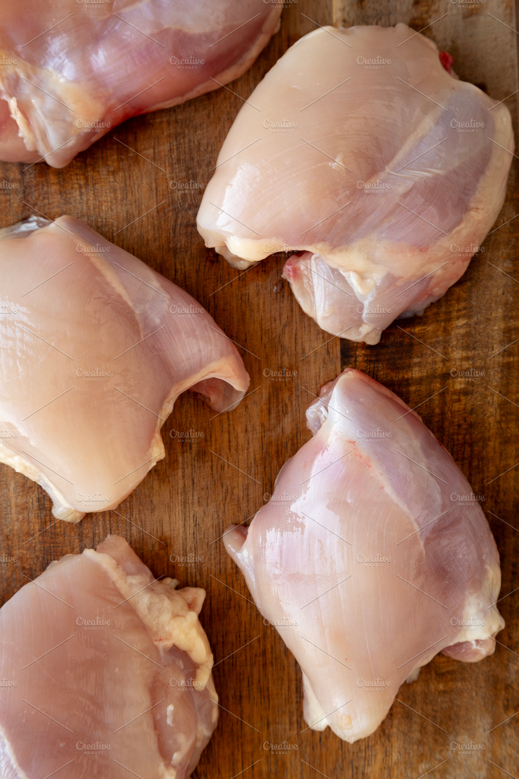 Raw Organic Boneless Skinless Chicken Thighs on a Wooden Board,, a Food & Drink Photo by LiudmylaChuhunova