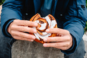 close-up of a man holding a danish kanelsnegl, a Photo by Nito