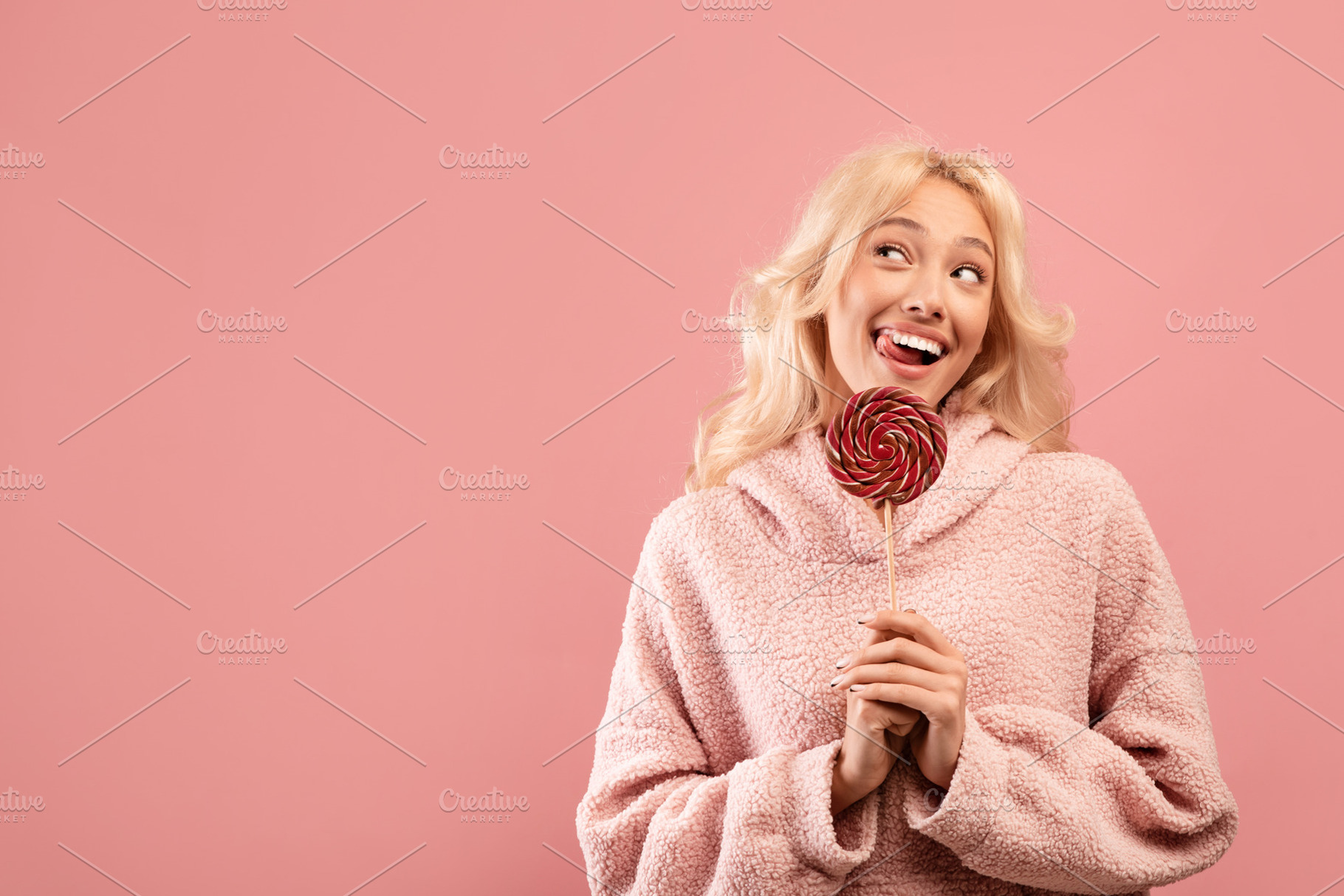 Sweet tooth concept. Playful lady holding candy on stick, looking aside at free, a Photo by Prostock-Studio