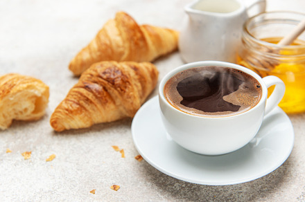 Steaming coffee, fresh croissants, and honey create a tempting b