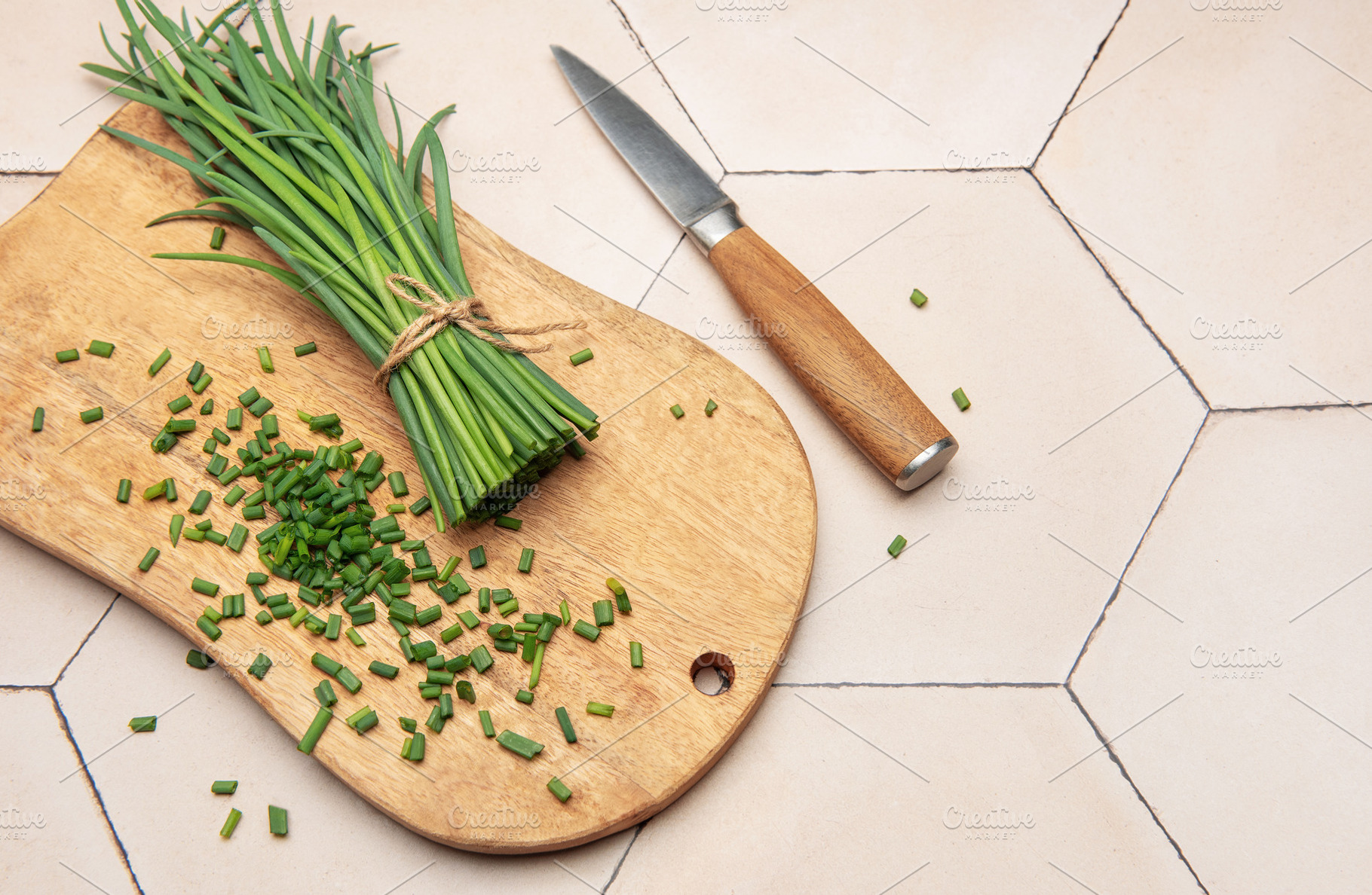 Freshly cut chives on wooden cutting board with knife, a Photo by Olena Rudo