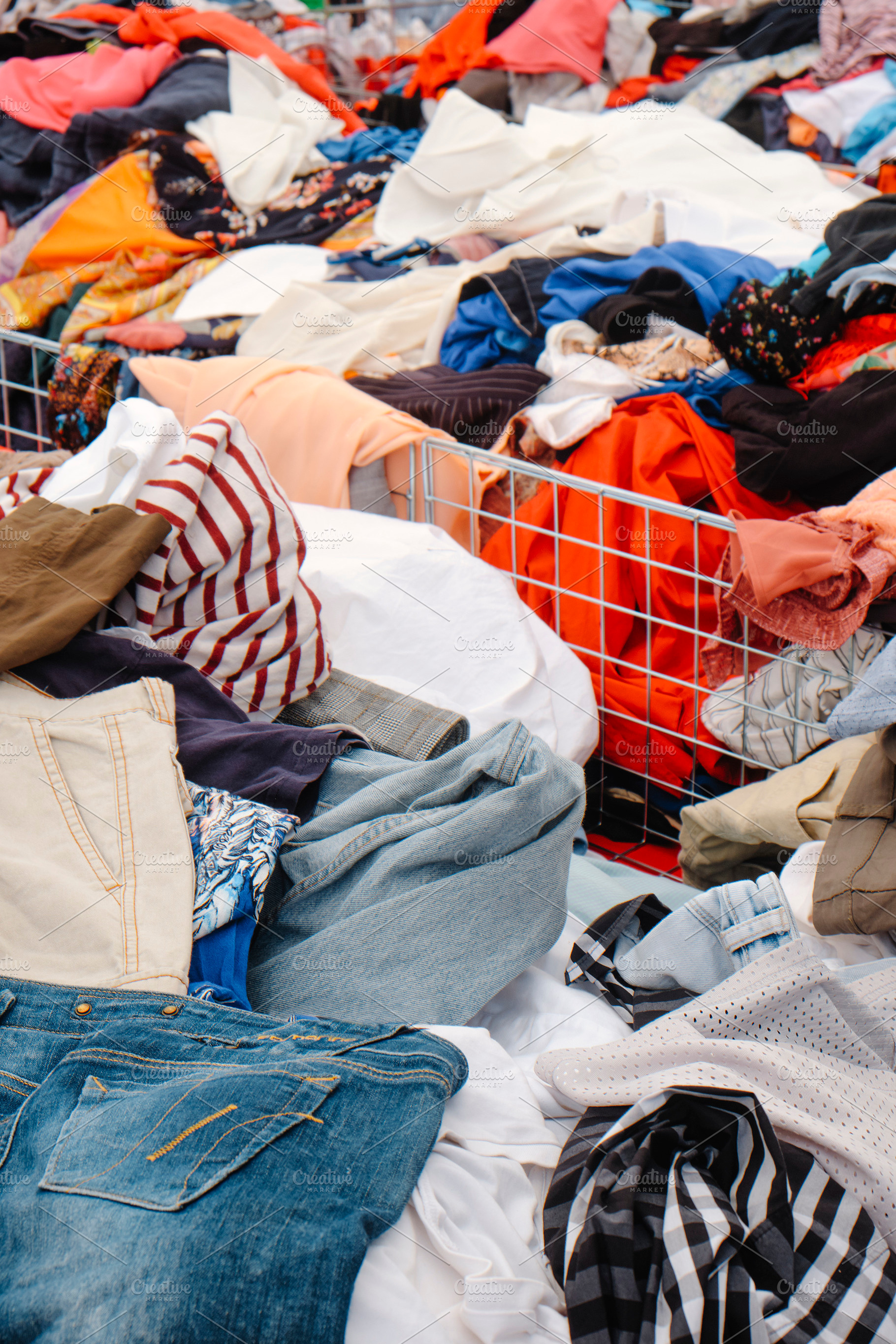 jeans and shirts filling bins at a busy outdoor stall, a Photo by Nito