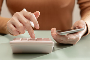 Woman using calculator and smartphone at desk. Personal finance, a Photo by salmon.black