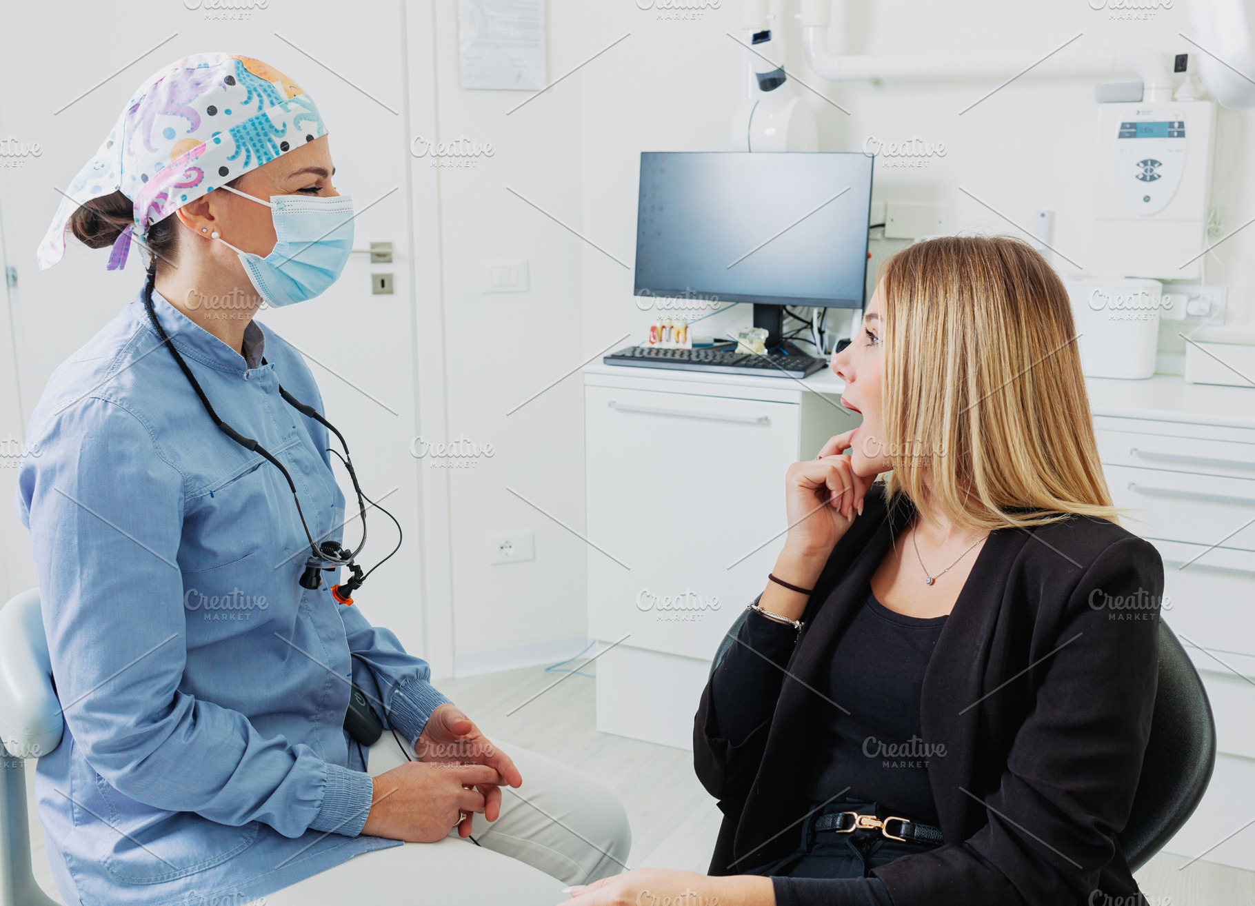 Dentist wearing surgical mask listening to patient explaining toothache in brig, a Health & Medical Photo by Antonio Gravante Market