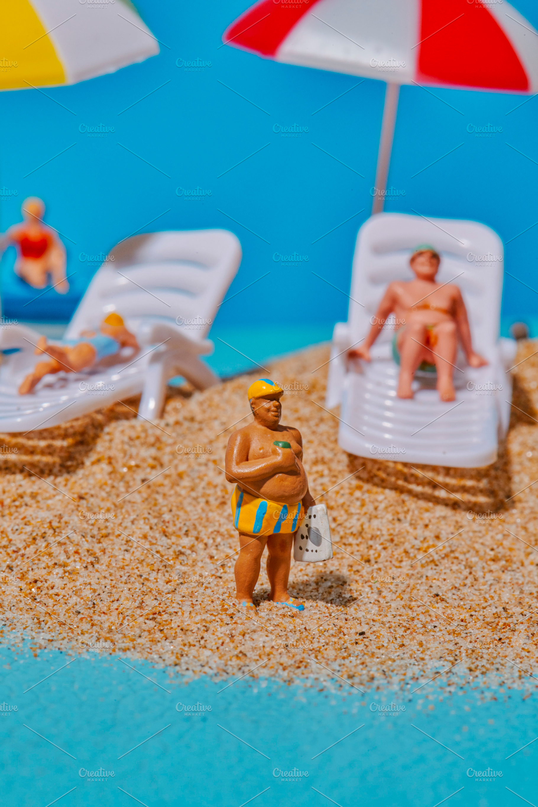 miniature man wearing striped shorts on the sand, a Photo by Nito