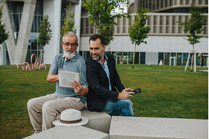 Father and adult son sitting on, a Person Photo by HalfPoint