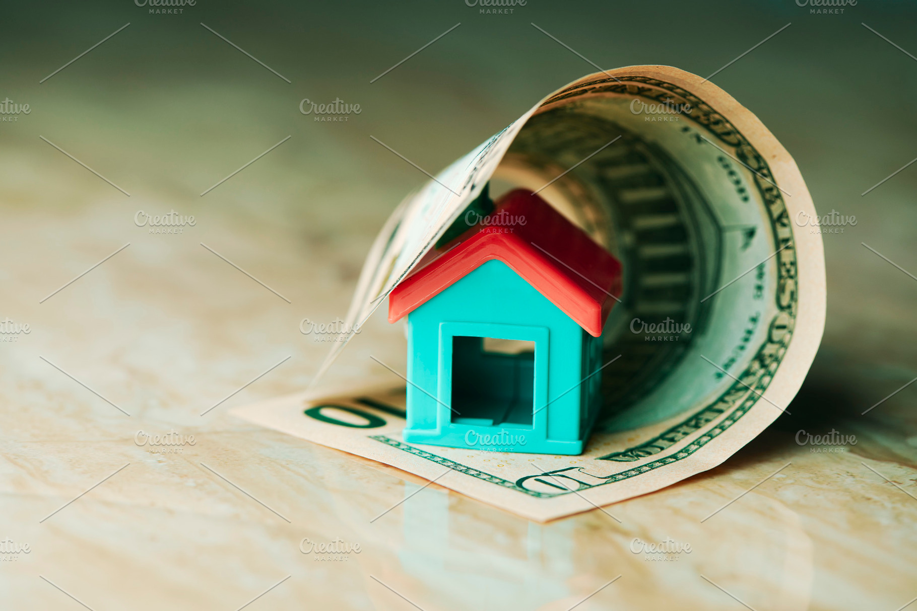 a toy house enclosed by a rolled dollar bill, a Photo by Nito