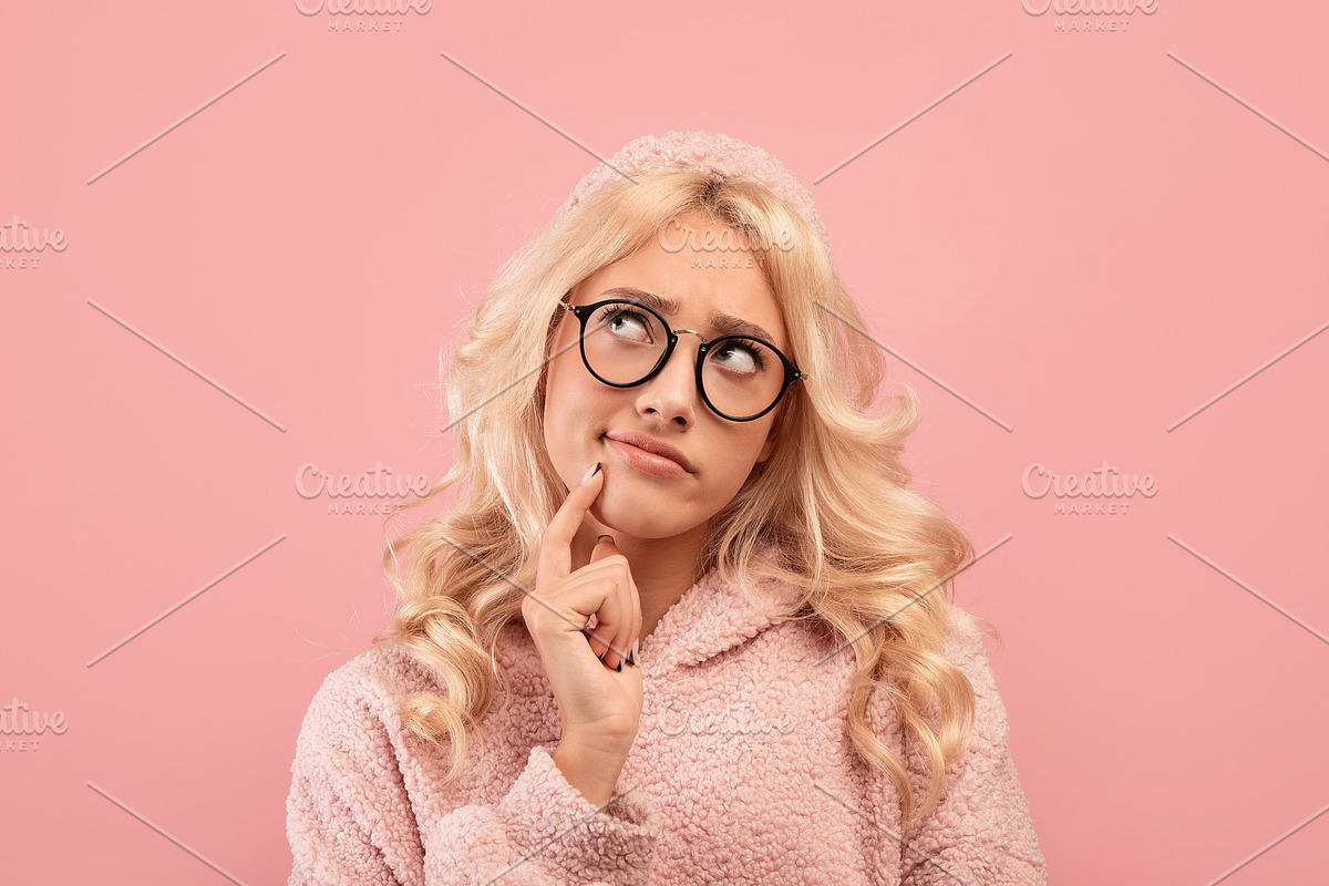 Portrait of pensive blonde lady touching chin and looking aside, posing on pink, a Photo by Prostock-Studio (Photo 2 of 2)
