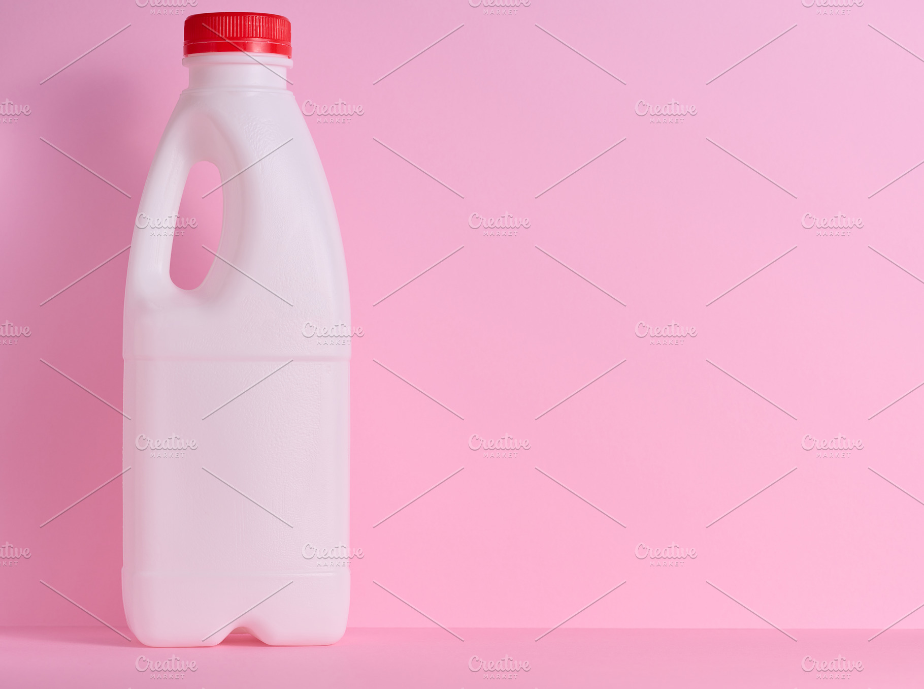 White plastic bottle for milk and dairy products on a pink backg, a Food & Drink Photo by ndanko
