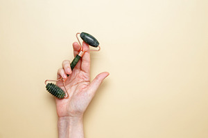 Female hands holding marble face roller tools for skincare routine, a Photo by matucha