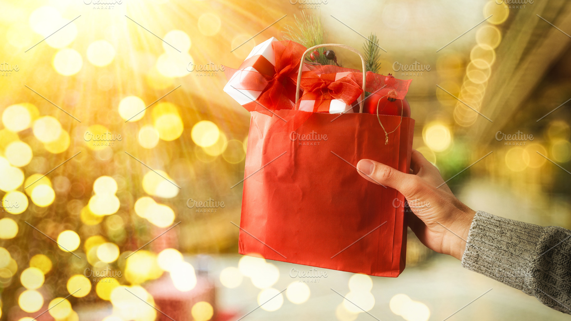 Hand holding shopping bag full of gifts outside sunny, a Holiday Photo by Davizro's Market