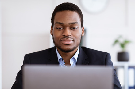 Closeup of handsome black businessman working with laptop, a Photo by Prostock-Studio