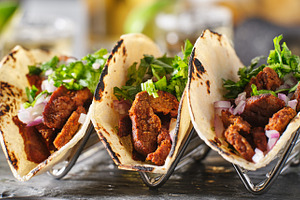 Carne asada tacos in taco holder containing food, tacos, and mexican