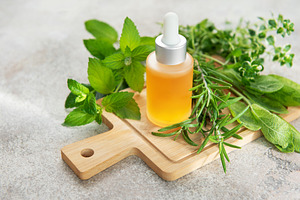 Essential oil bottle with natural herbs and plants on board, a Food & Drink Photo by Olena Rudo