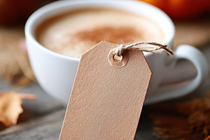 Cozy autumn vibes with a pumpkin latte and kraft tag on a rustic wooden table, a Food & Drink Photo by AlyaAnd