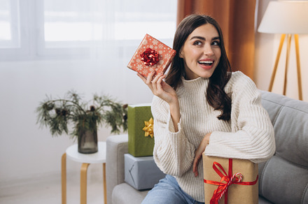 Beautiful happy woman unwrapping New Year or Christmas presents