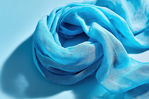Elegant blue scarf on light background, an Abstract Photo by AlyaAnd