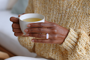 Softly glowing ring held in warm autumn light with a cup of tea, a Photo by AlyaAnd