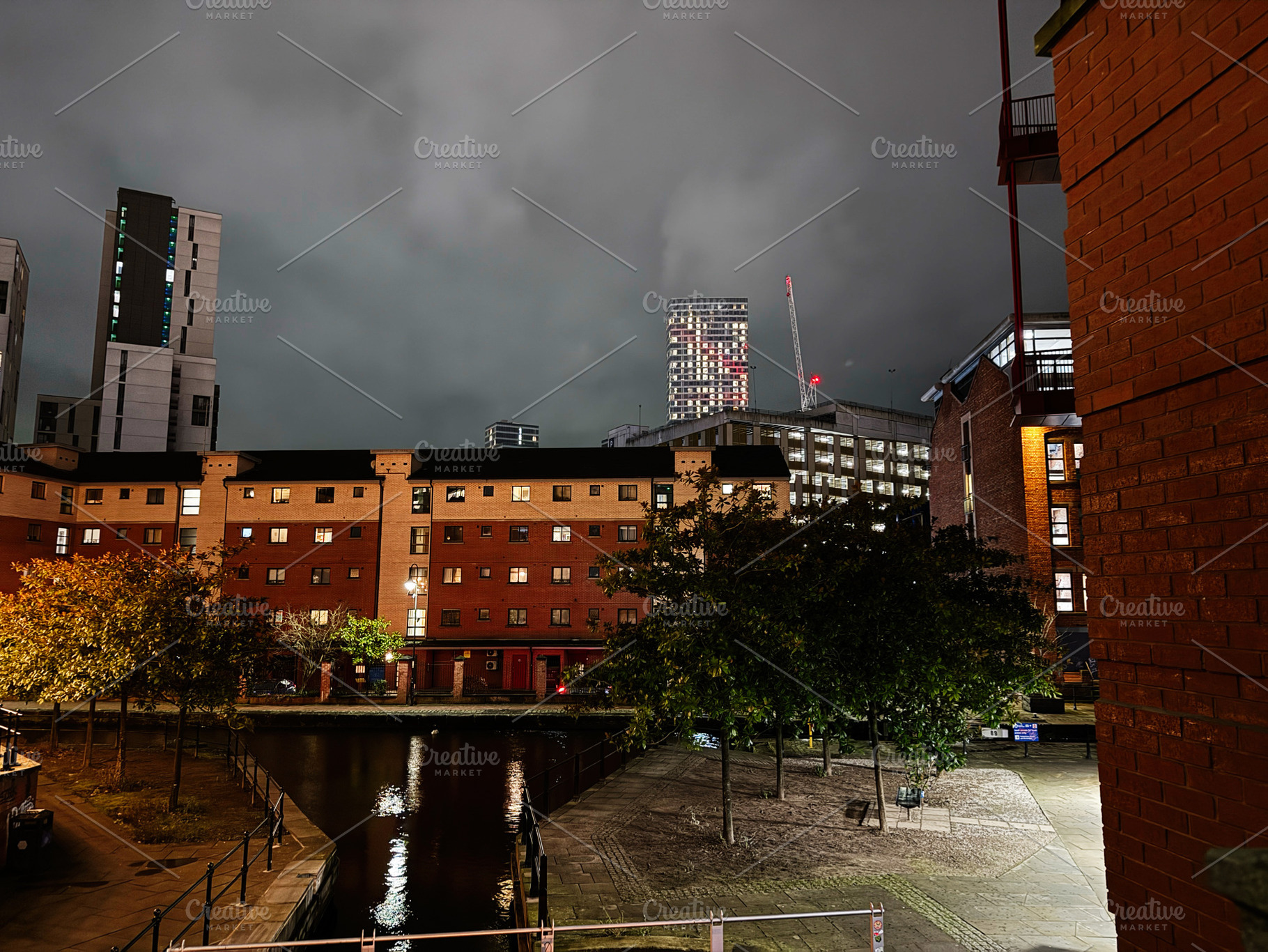 Night cityscape in Manchester with brick buildings canal and modern high rise u, a Photo by AS photostudio