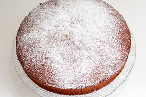 Delicious homemade caprese cake resting on a glass cake stand, sprinkled with p, a Food & Drink Photo by Antonio Gravante Market