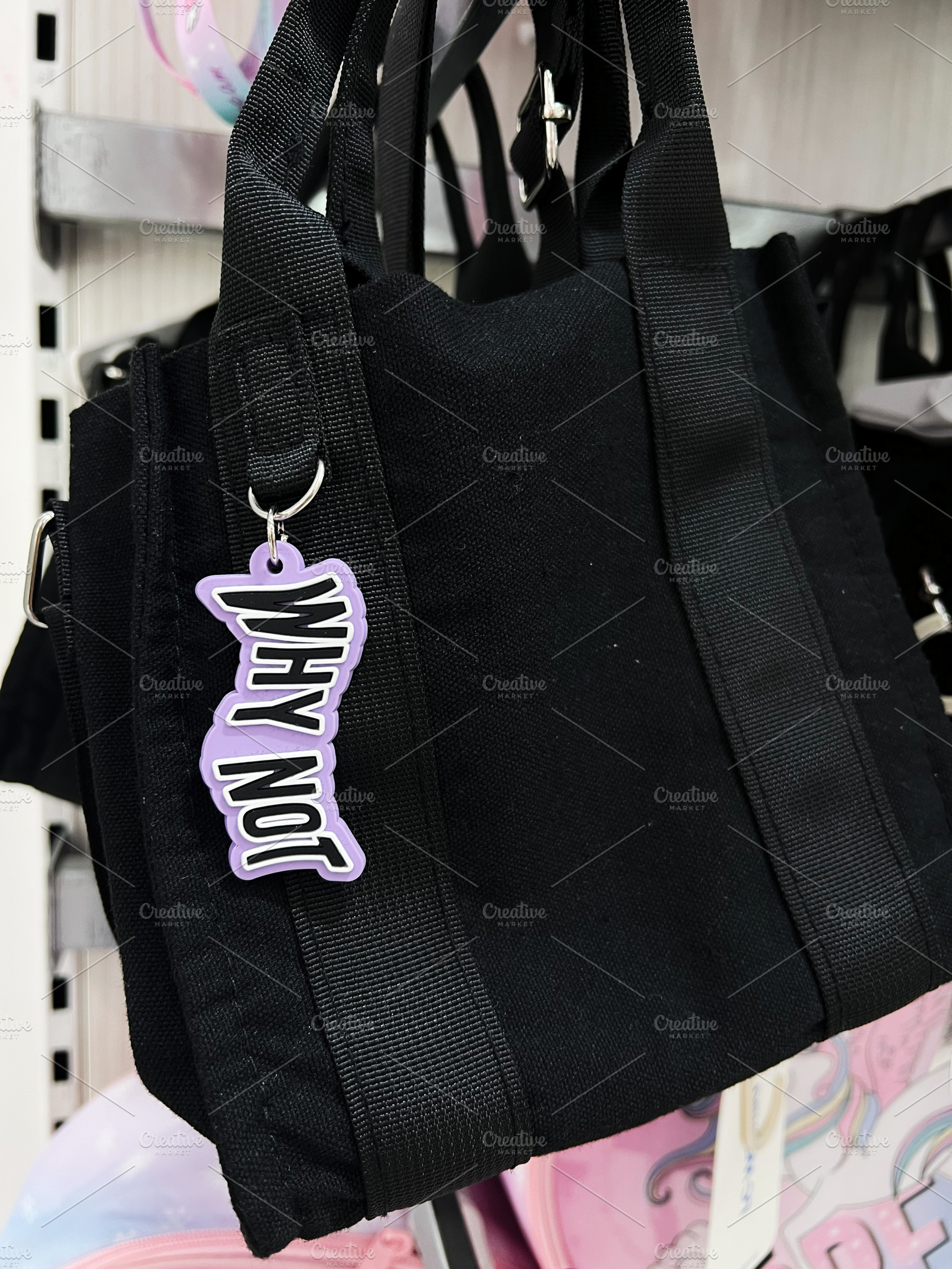 Black tote bag featuring a stylish keychain Why Not displayed on a retail shelf, a Photo by AS photostudio