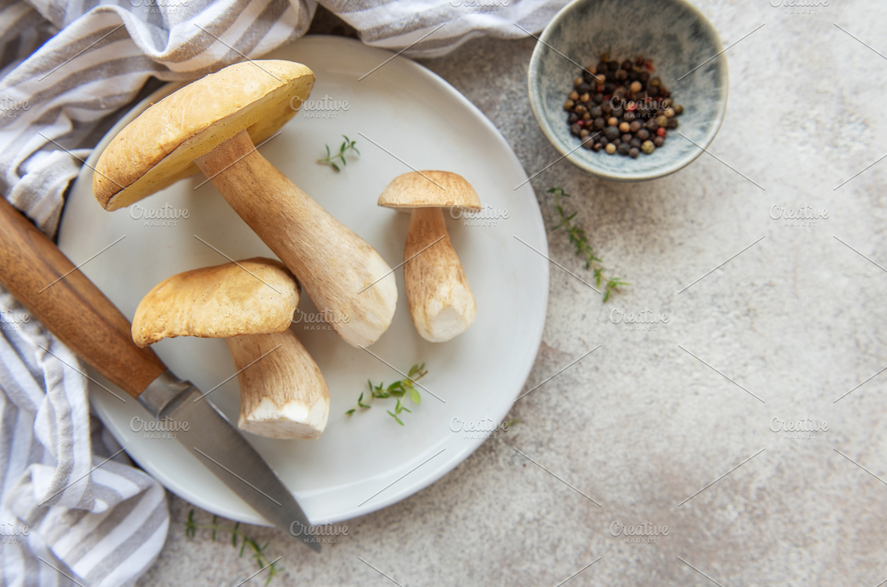 Fresh porcini mushrooms on plate with knife and peppercorns read, a Food & Drink Photo by Olena Rudo