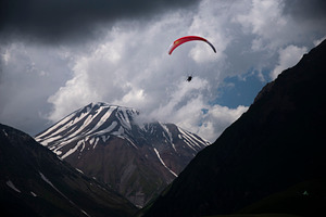 Paraglider flying over snow covered mountains under storm clouds, a Photo by Pictures for you!!!!!!!!!