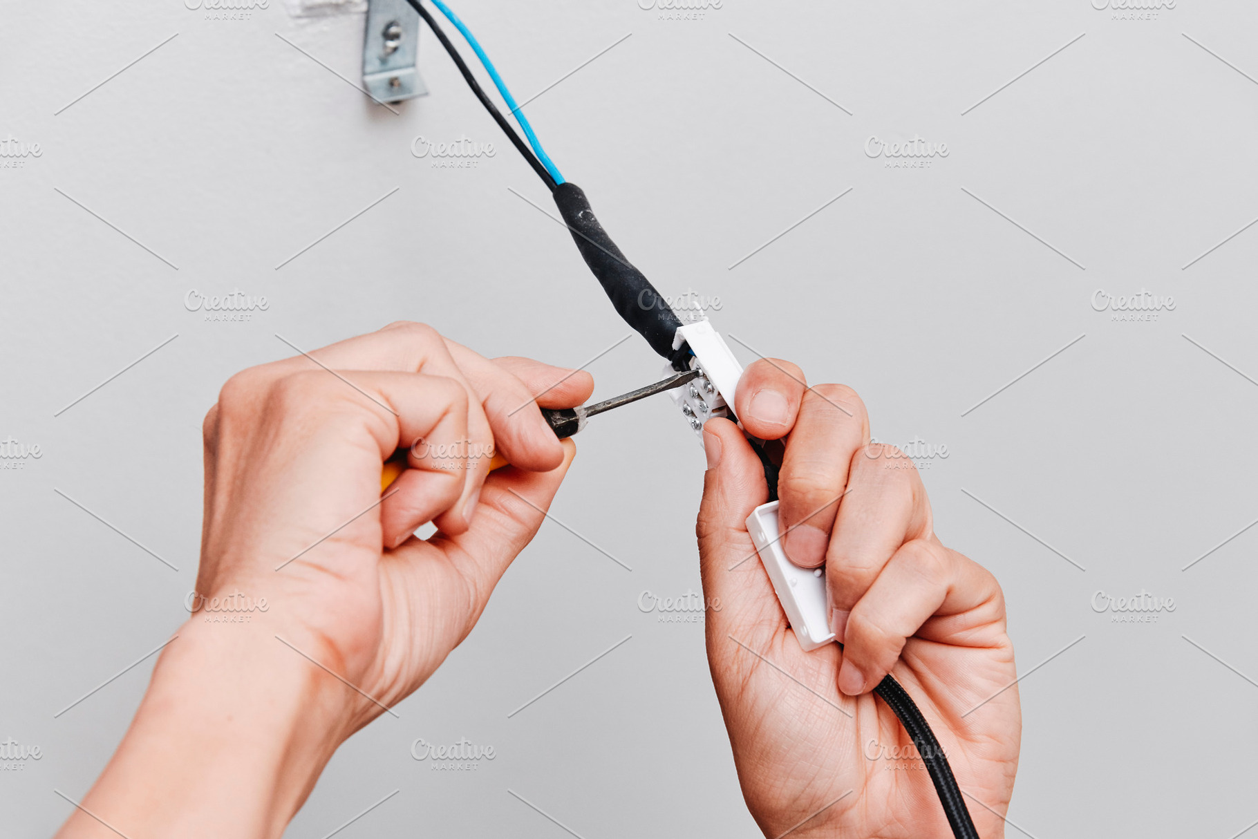 a close-up of a man connecting a ceiling light, a Photo by Nito
